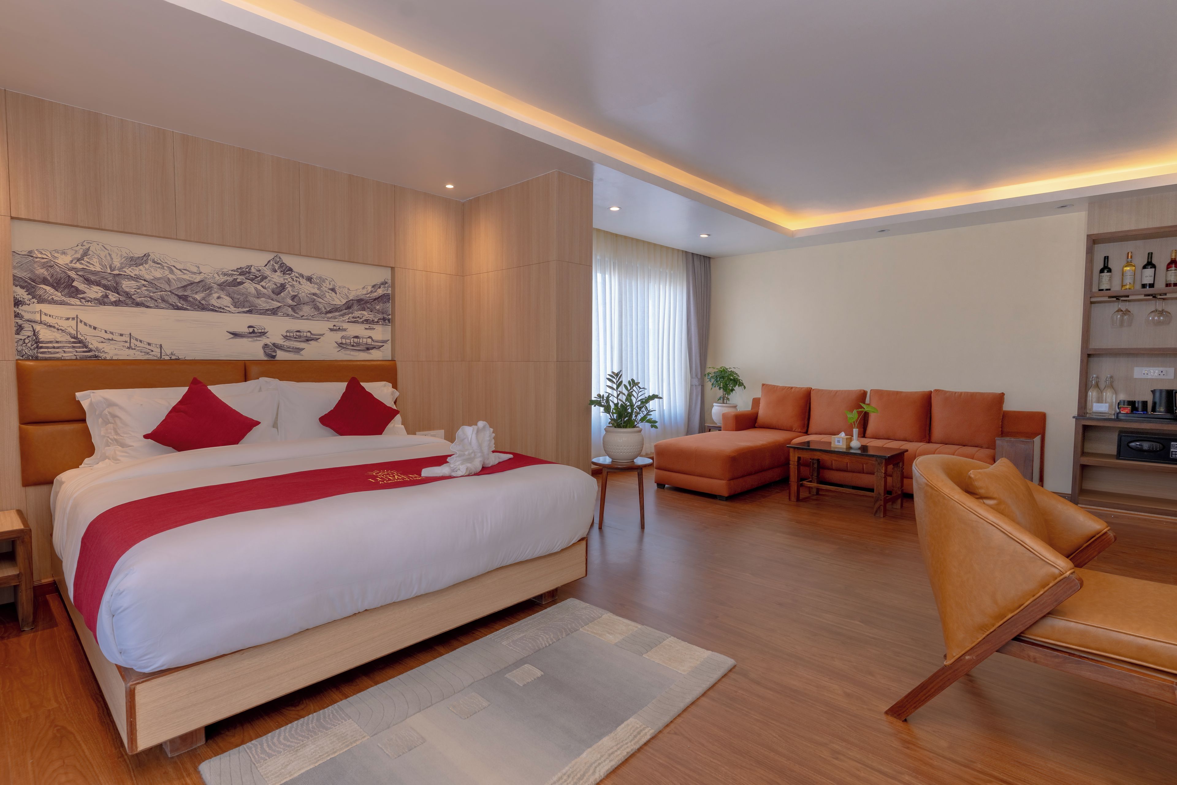 Habitación de hotel con una cama grande, un sofá, una mesita y un estante en la pared con botellas.