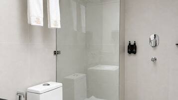 A modern bathroom with a glass-enclosed shower, a white toilet, and a black countertop.