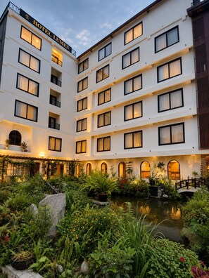 Een meerlaags hotel met een binnentuin, inclusief een fontein en weelderige begroeiing.