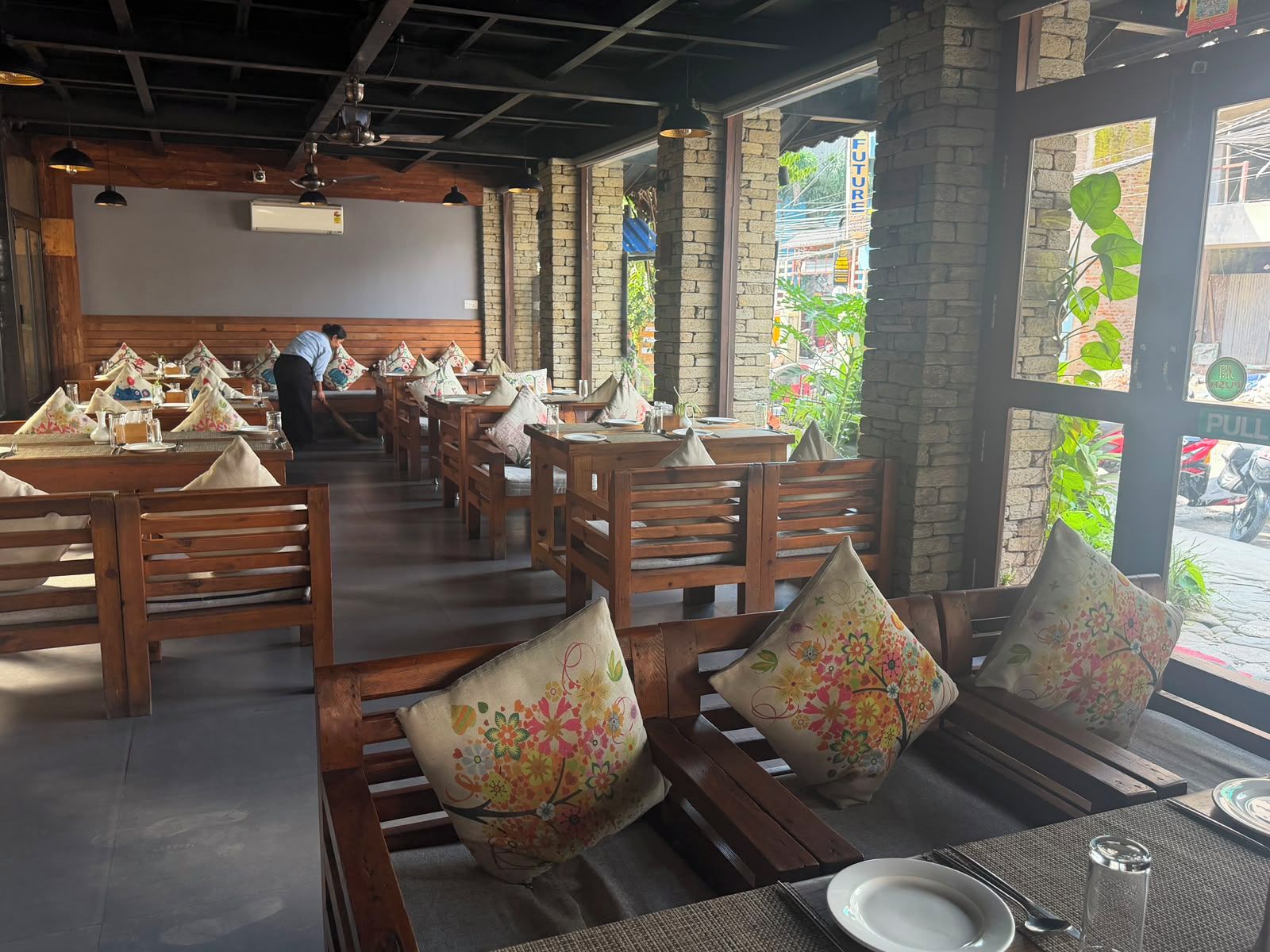 A restaurant with wooden tables and benches, some with floral cushions.