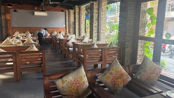 A restaurant with wooden tables and benches, some with floral cushions.