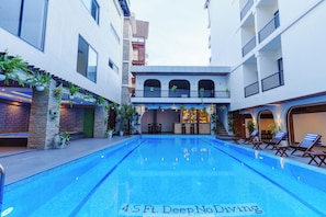 Una piscina con zona de bar y sillones de descanso.