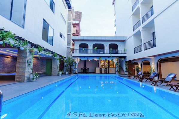 A swimming pool with a bar area and lounge chairs.