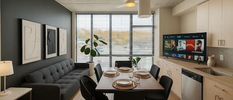 Un espacio habitable moderno con comedor, sofá, televisión y cocina.
