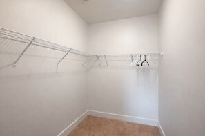Ein kleiner, weiß geflieste Schrank mit einer Metallregaleinheit und einer Kleiderstange.