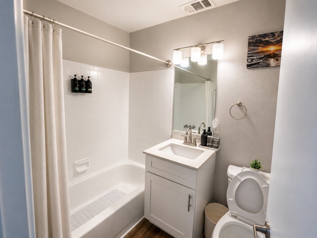 A bathroom with a bathtub, a sink with a mirror, and a toilet.