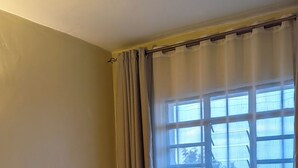 Ein Schlafzimmer mit einem Bett, Vorhängen und einem Fenster.
