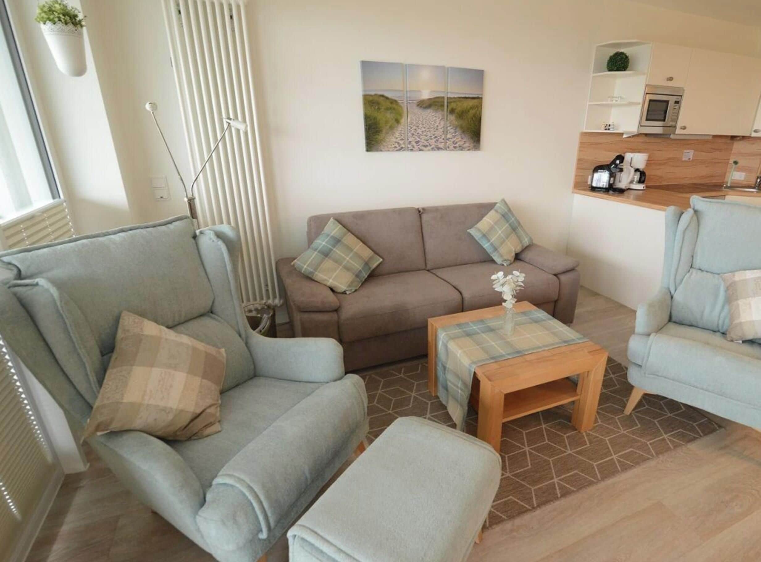 A living room with a sofa, a coffee table, and a kitchen area in the background.