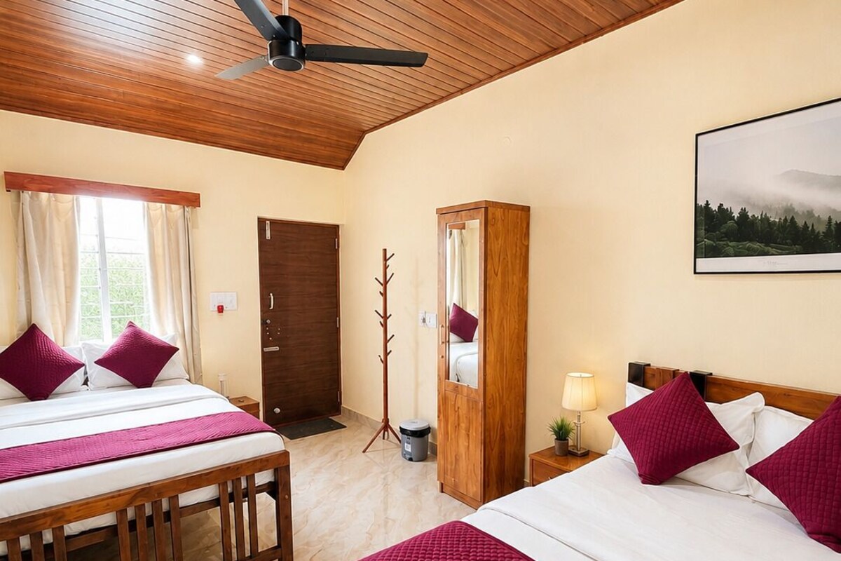 A hotel room with two beds, a wooden ceiling, a large window, and a painting on the wall.