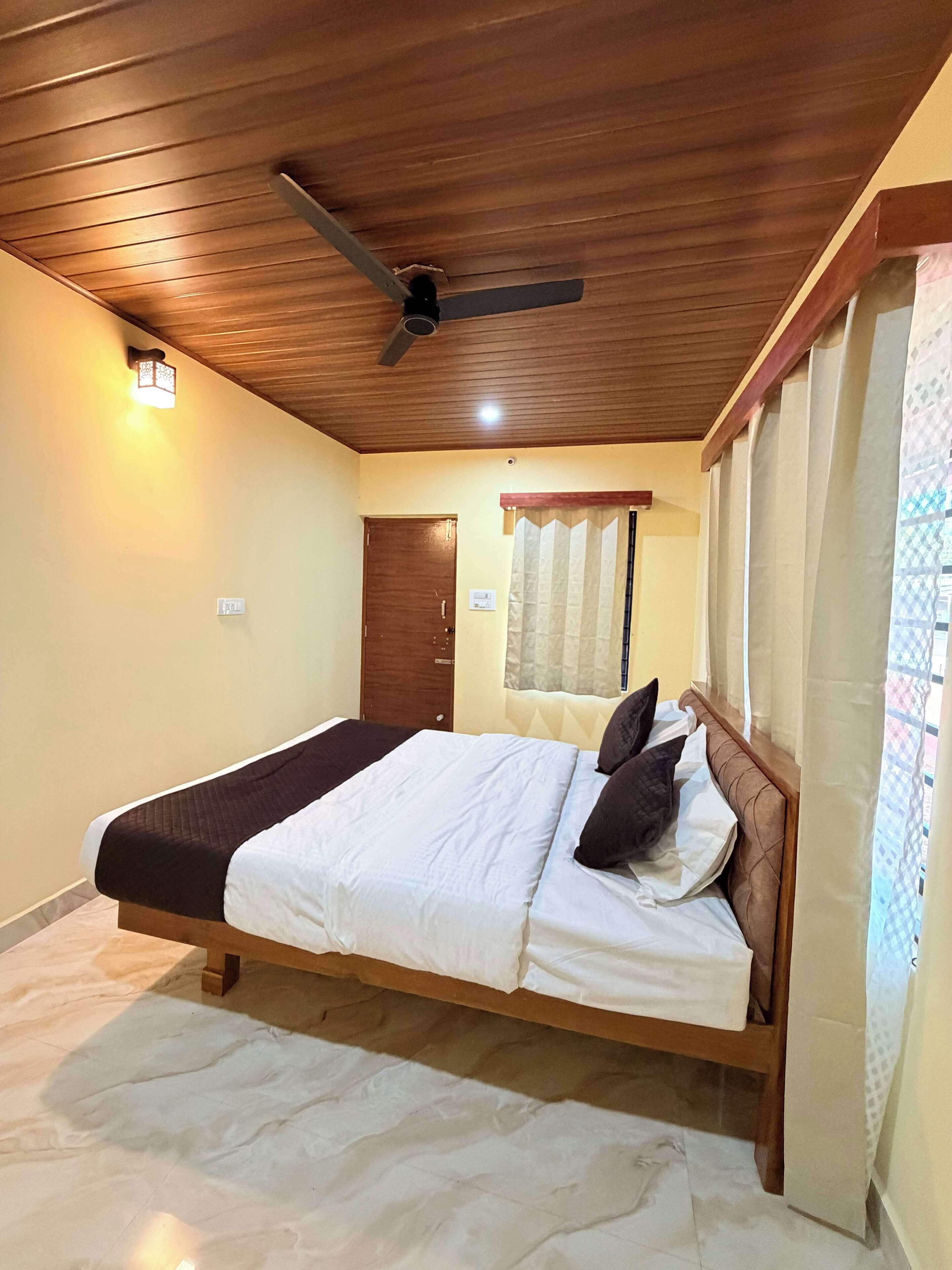 Un dormitorio con cama, techo de madera, ventilador de techo y ventana con cortinas.