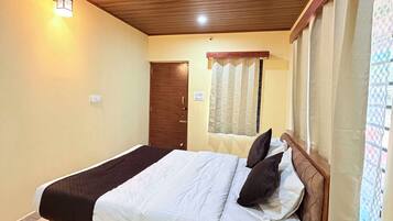 Un dormitorio con cama, techo de madera, ventilador de techo y ventana con cortinas.