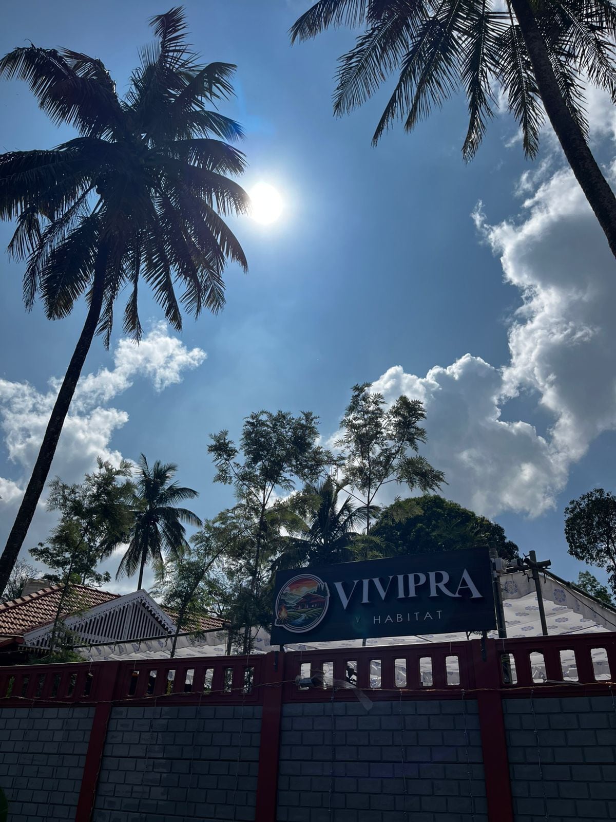 A sign for 'VIVIPRA HABITAT' with a clear sky and palm trees in the background.