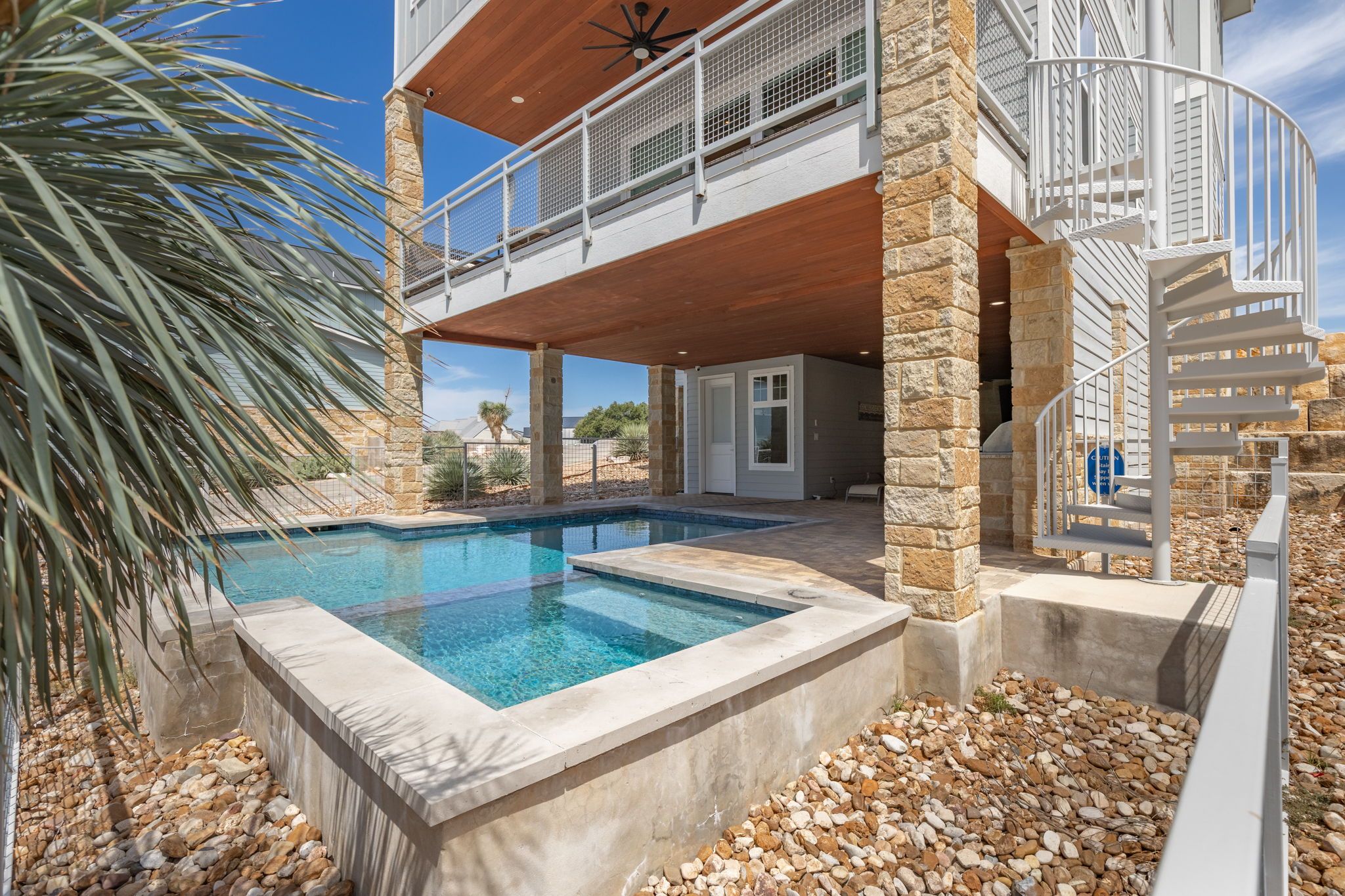 A modern house with a swimming pool, stone pillars, and a balcony.