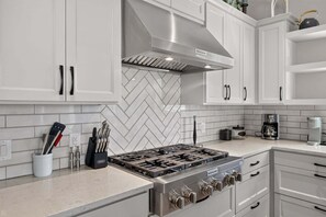 A modern kitchen with white cabinetry, a stainless steel range, and a herringbone tile backsplash. - 🌊 New - Lakeview at LBJ - Private Pool, Hot Tub, Sleeps 14 ✨ (Kingsland)