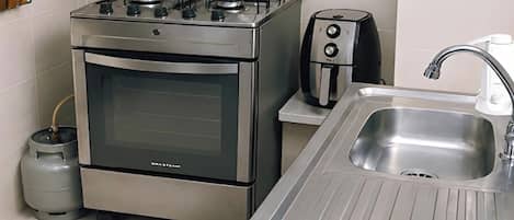 Una cocina con estufa de acero inoxidable, cafetera y lavaplatos.