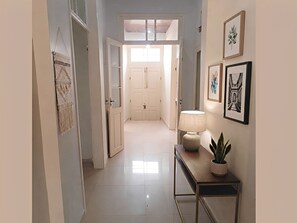 A hallway with a door at the end, a wall-mounted lamp, and framed artwork. - Casarão São Chico: A cozy, historic colonial mansion overlooking Babitonga Bay. (São Francisco do Sul)