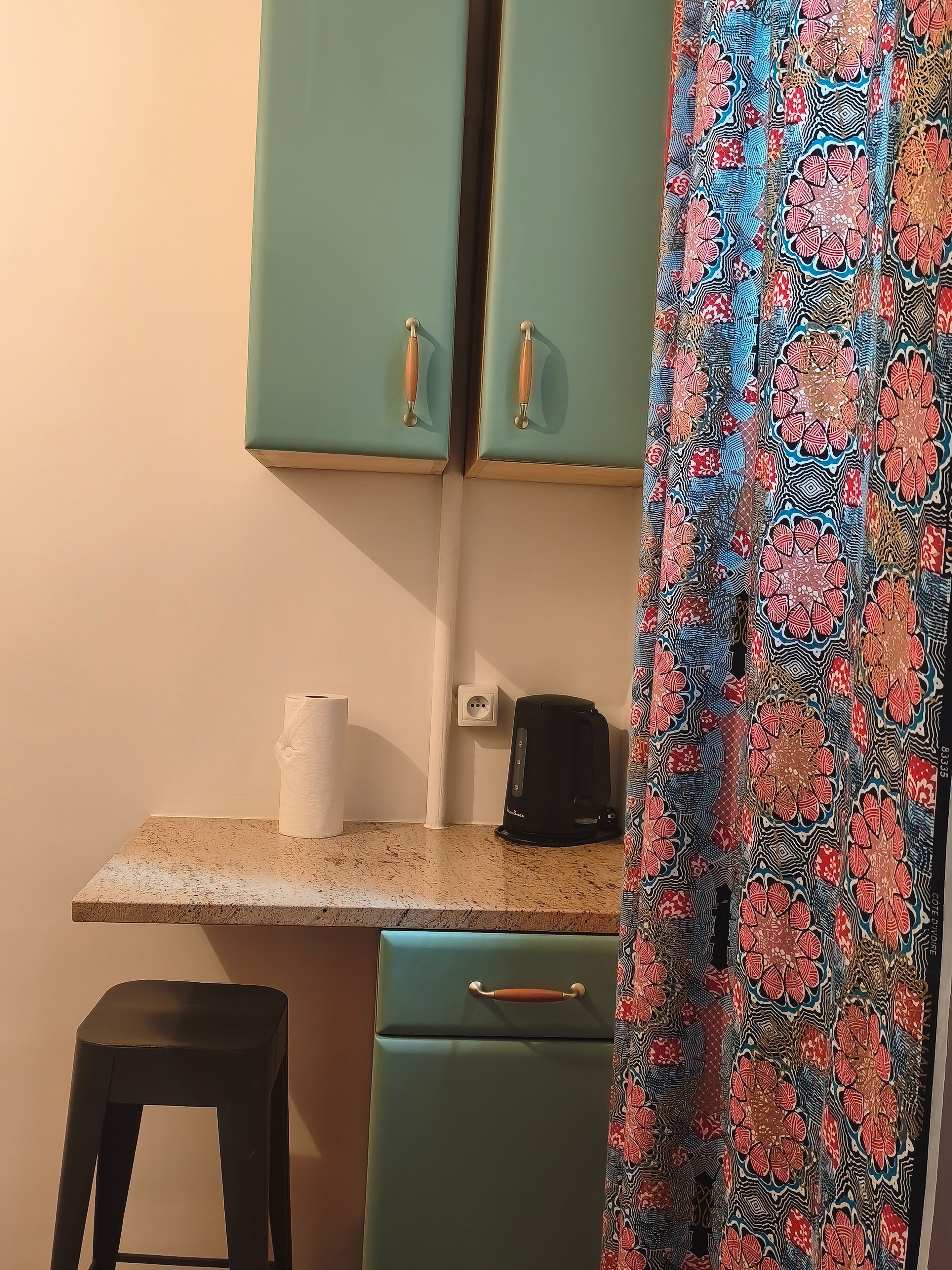 Une petite cuisine équipée d’un plan de travail, d’un petit réfrigérateur, d’une machine à café et d’un tabouret de bar.