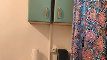 Une petite cuisine équipée d’un plan de travail, d’un petit réfrigérateur, d’une machine à café et d’un tabouret de bar.