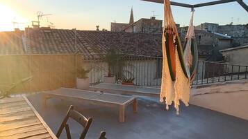 Una terrazza panoramica con tavolo e sedie, un'amaca e piante in vaso.