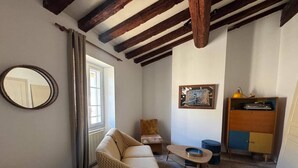 Una habitación acogedora con un sillón estampado, una mesita, un mueble con un tocadiscos y un espejo en la pared.