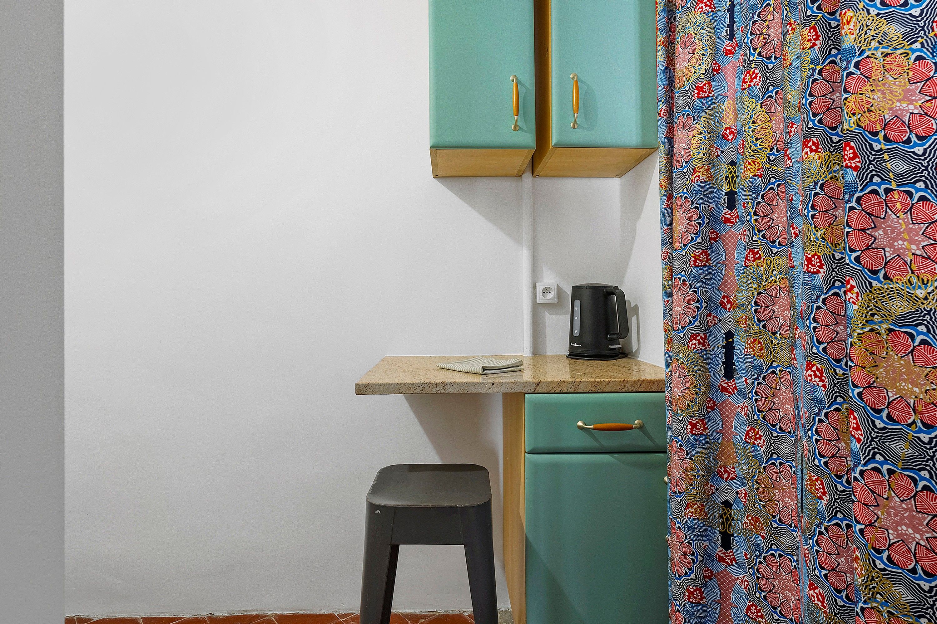 A kitchenette with a small countertop, a coffee maker, and a stool.