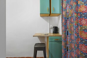 Una kitchenette con una pequeña encimera, una cafetera y un taburete.