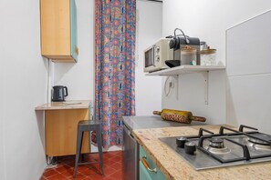 Una cocina funcional con estufa a gas, microondas y una pequeña encimera.