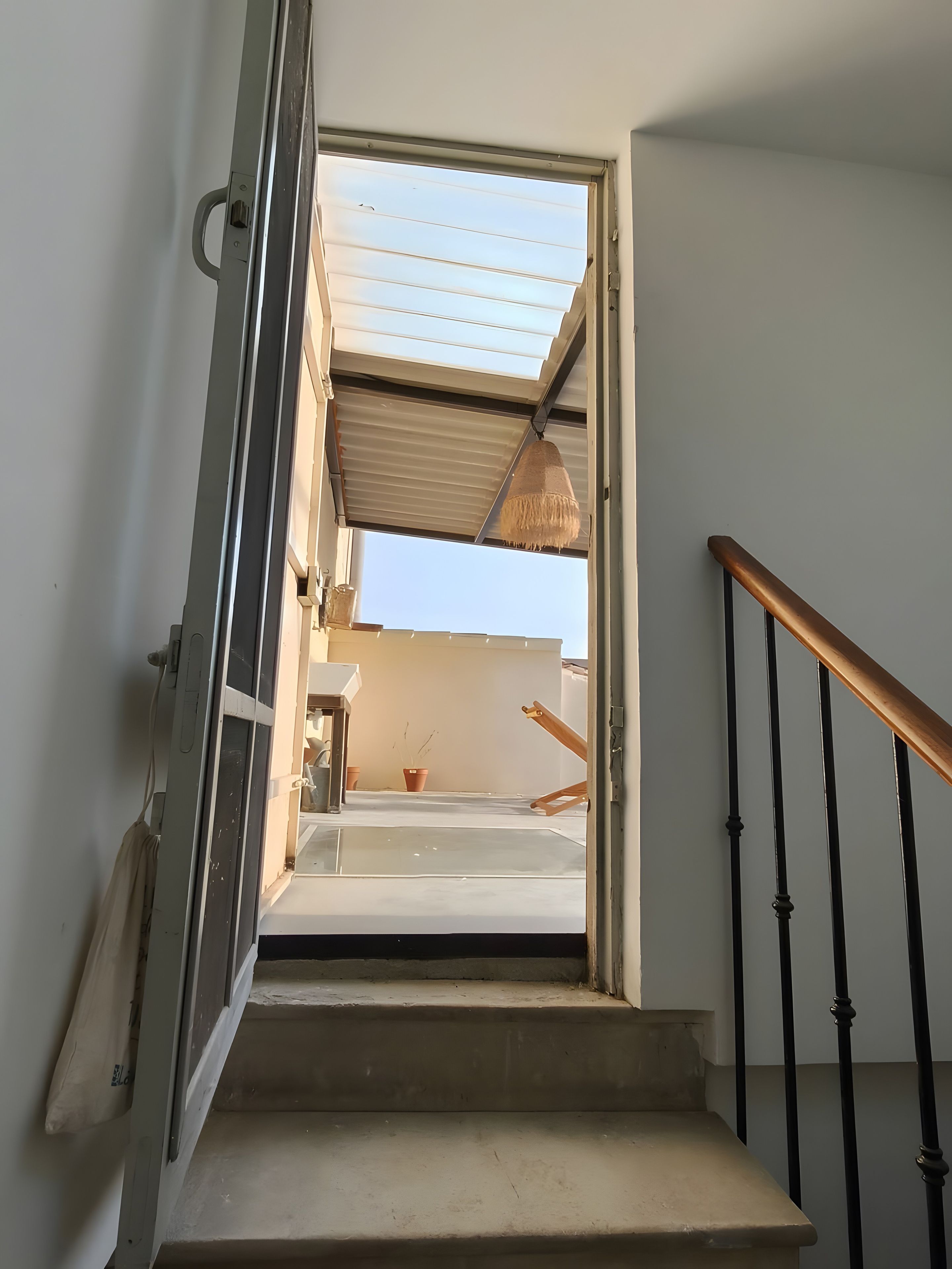 Un escalier avec une rampe métallique menant à une porte ouverte.