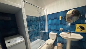 Un baño con ducha acristalada, inodoro, lavabo y lavadora.
