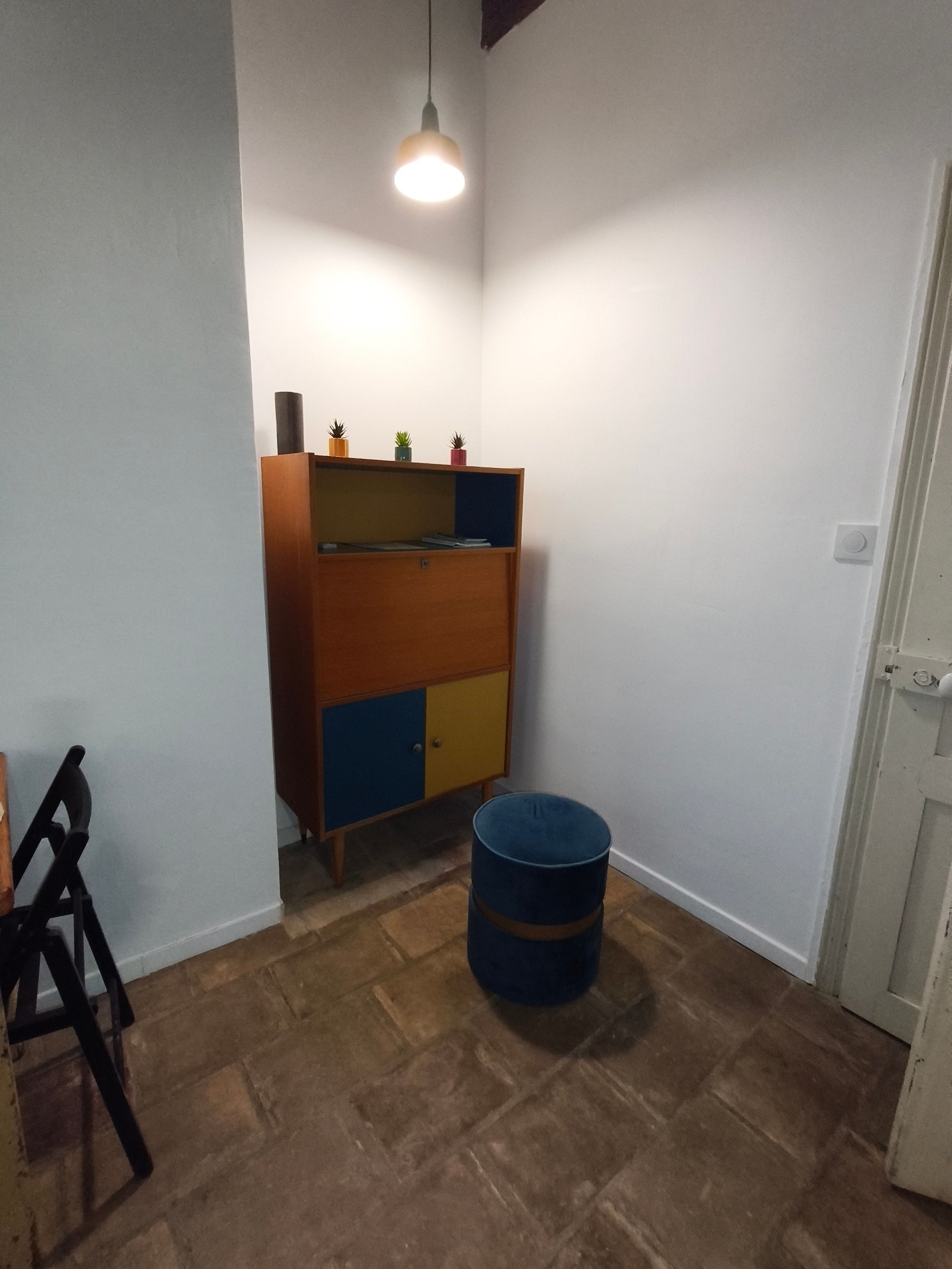 Una stanza con un armadio di legno, una botte blu e un lampadario.