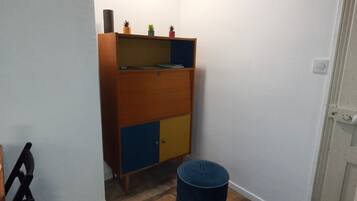 Una stanza con un armadio di legno, una botte blu e un lampadario.