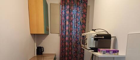 Cocina compacta con estufa a gas, microondas, una mesita y una silla.