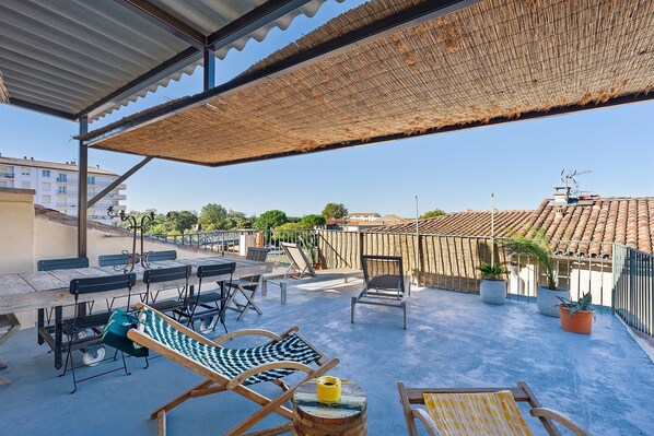 Een terras op het dak met buitenmeubilair, een pergola en uitzicht op de stad.