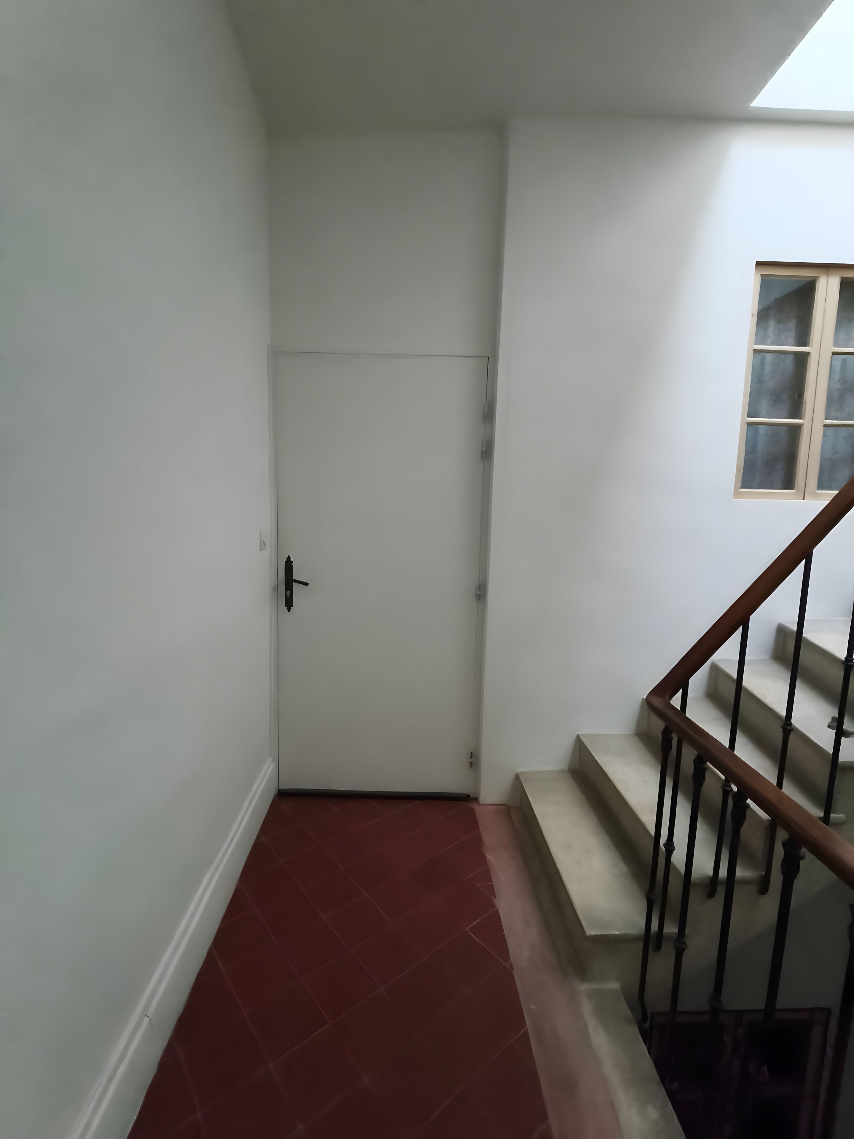 Una scala con ringhiera in legno e una porta con maniglia nera.