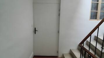 Una scala con ringhiera in legno e una porta con maniglia nera.