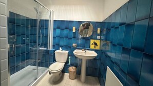 Un baño con cabina de ducha de vidrio, inodoro, lavamanos y espejo.