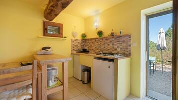 A compact kitchen with a wooden table, a small refrigerator, and a tiled backsplash.