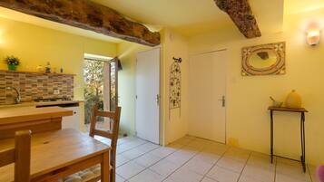 Une cuisine avec un coin repas, une porte blanche et un sol carrelé.
