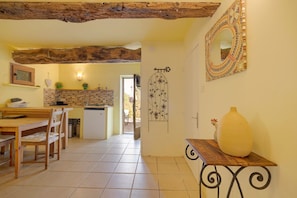 Une cuisine avec un plafond en bois, un coin repas avec une table et des chaises, et un miroir décoratif accroché au mur.