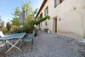 Un espace extérieur aménagé avec une table et des chaises, un parasol et un sol recouvert de gravier.
