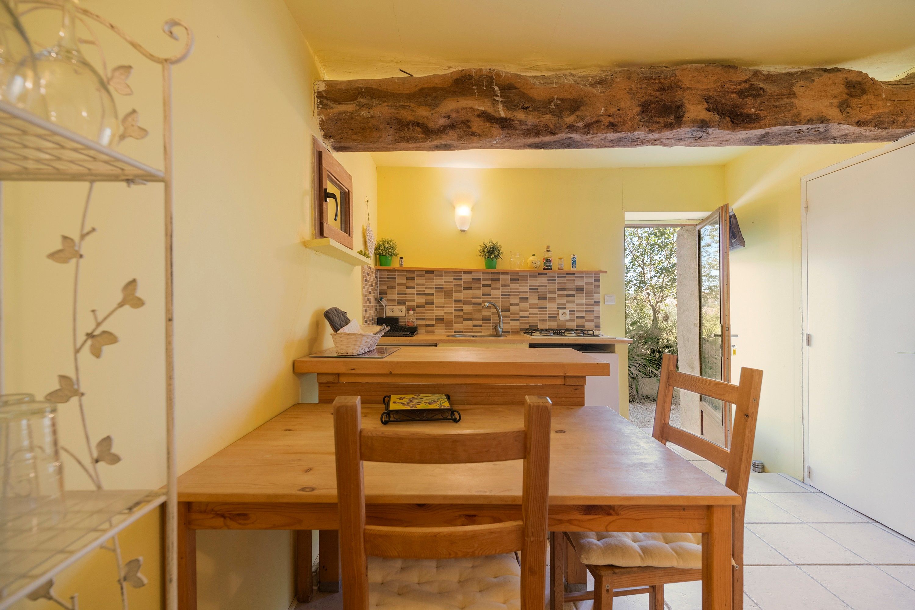 Een keuken met een houten tafel en stoelen, een betegelde spatwand en een hanglamp.