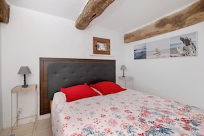 Une chambre à coucher avec un grand lit, deux lampes de chevet, une tête de lit en bois et une petite fenêtre.
