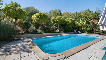 Une piscine rectangulaire à l’eau d’un bleu limpide, entourée d’une terrasse carrelée.