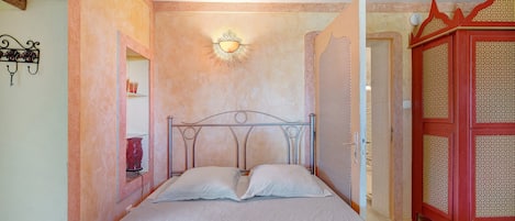 Une chambre à coucher avec un lit, un luminaire fixé au mur et une armoire rouge.