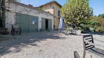 Un bâtiment doté d’un toit en tuiles, d’une cour en gravier et de mobilier d’extérieur.