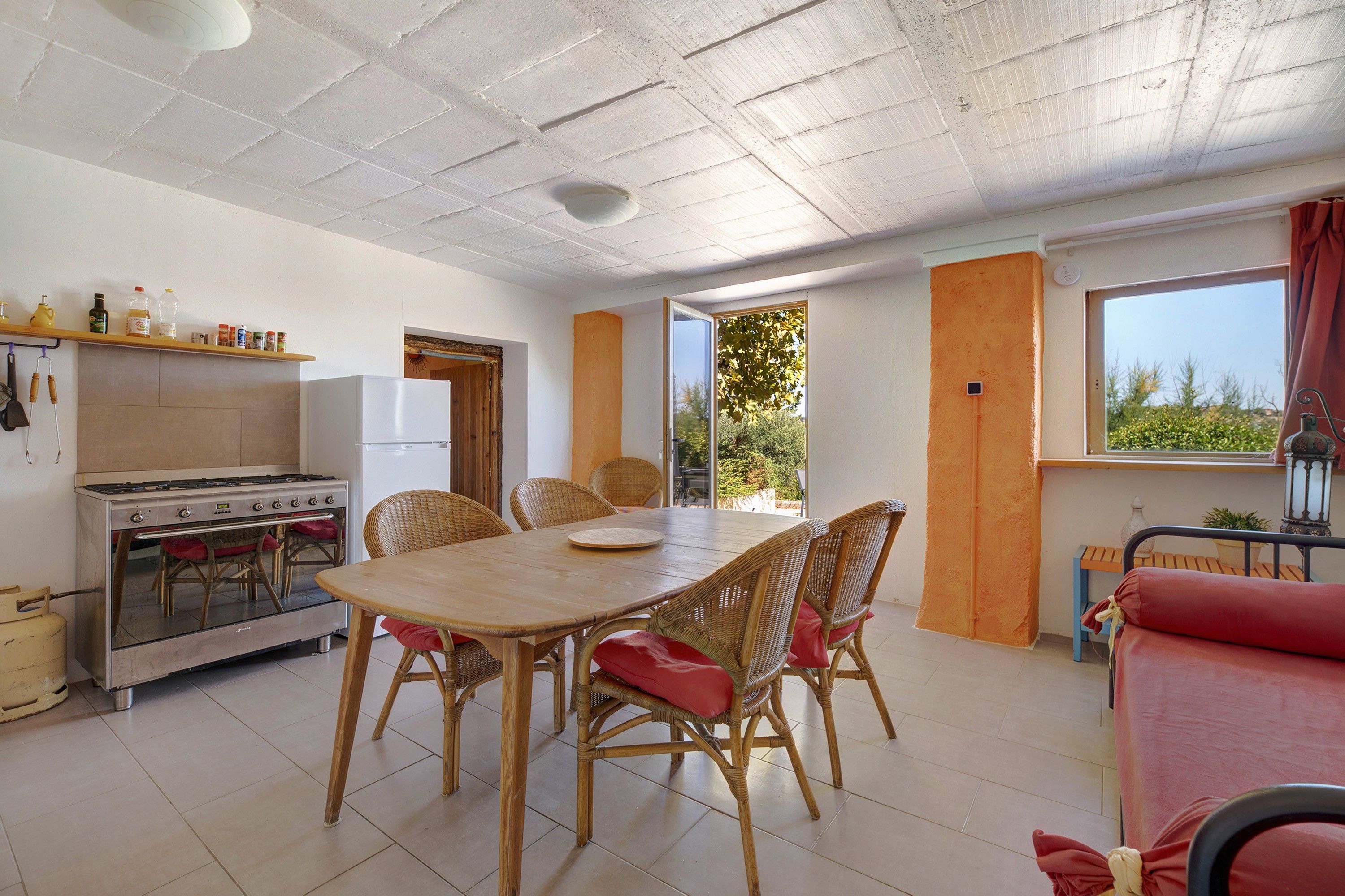 Une cuisine compacte équipée d’une cuisinière, d’un réfrigérateur et d’un coin repas avec des chaises en osier.