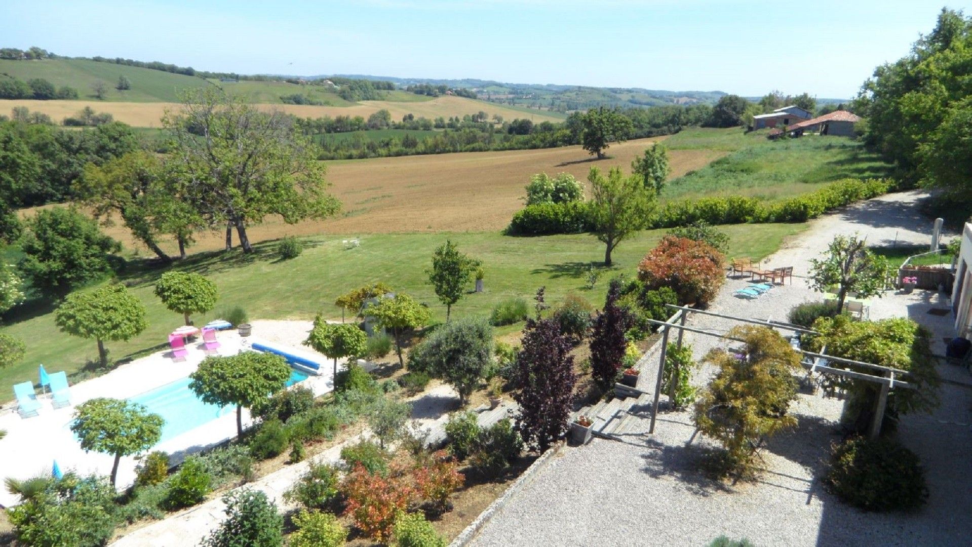 A residential property with a swimming pool, outdoor seating, and a view of rolling hills.