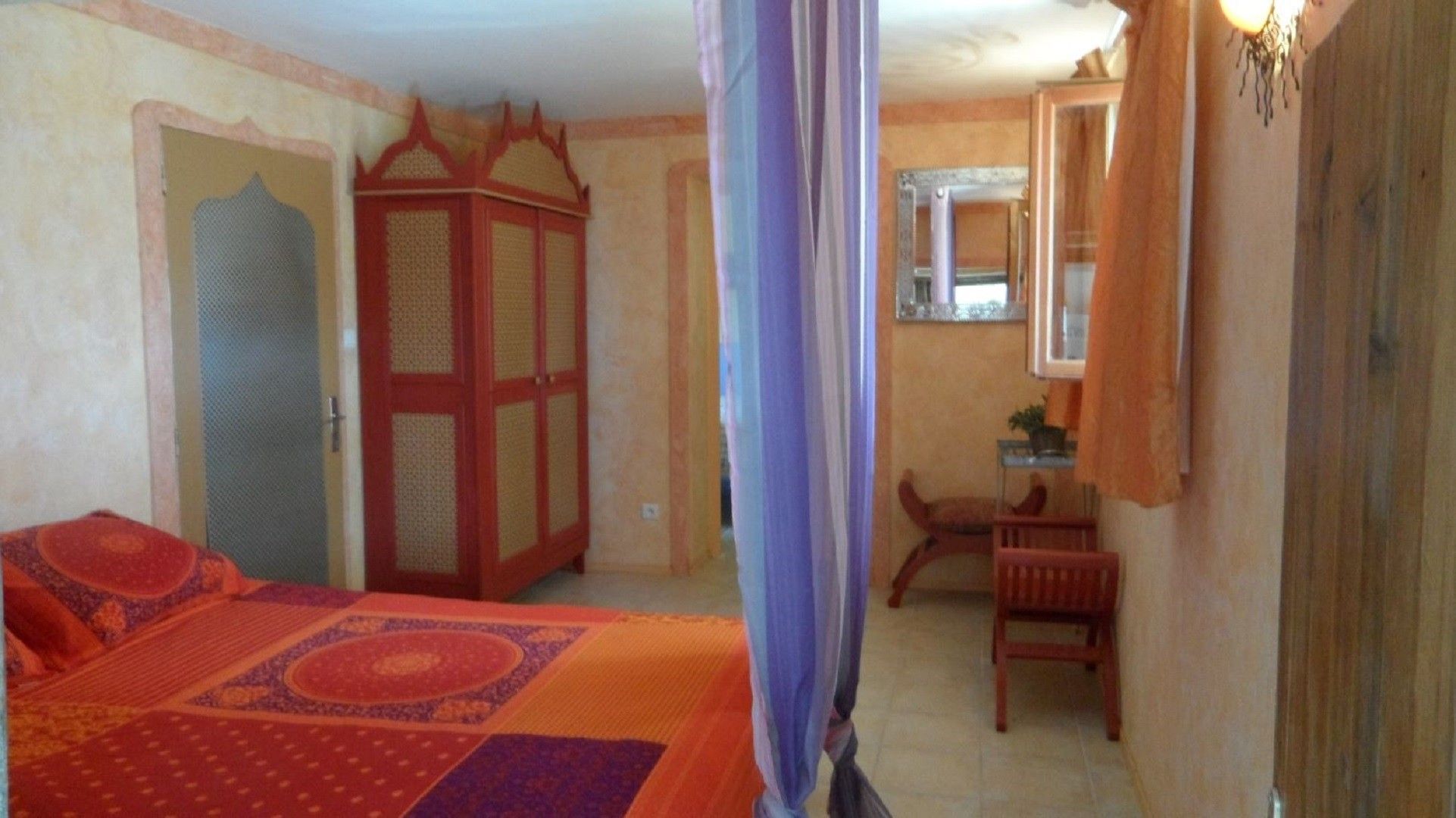 A bedroom with a bed, a wardrobe, a chair, and a window.