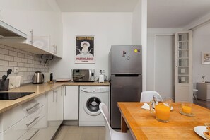 A modern kitchen with white cabinetry, a stainless steel refrigerator, a microwave, a kettle, and a washing machine. - Vintage-Chic Apartment in the City Center, Chiado (Lisboa)