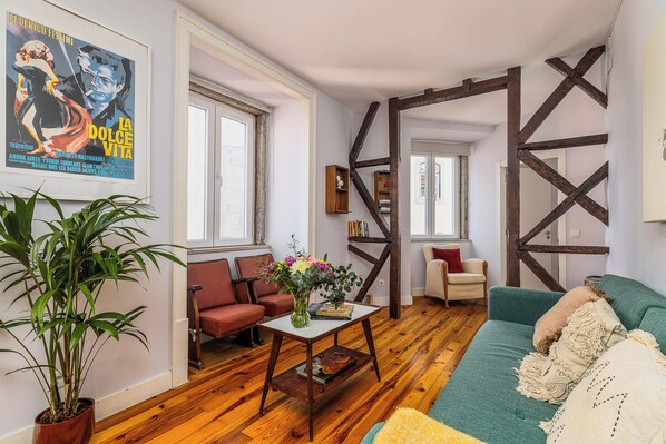 A living room with a wooden floor, a sofa, a coffee table, and a potted plant. - Vrbo Property (Lisboa)